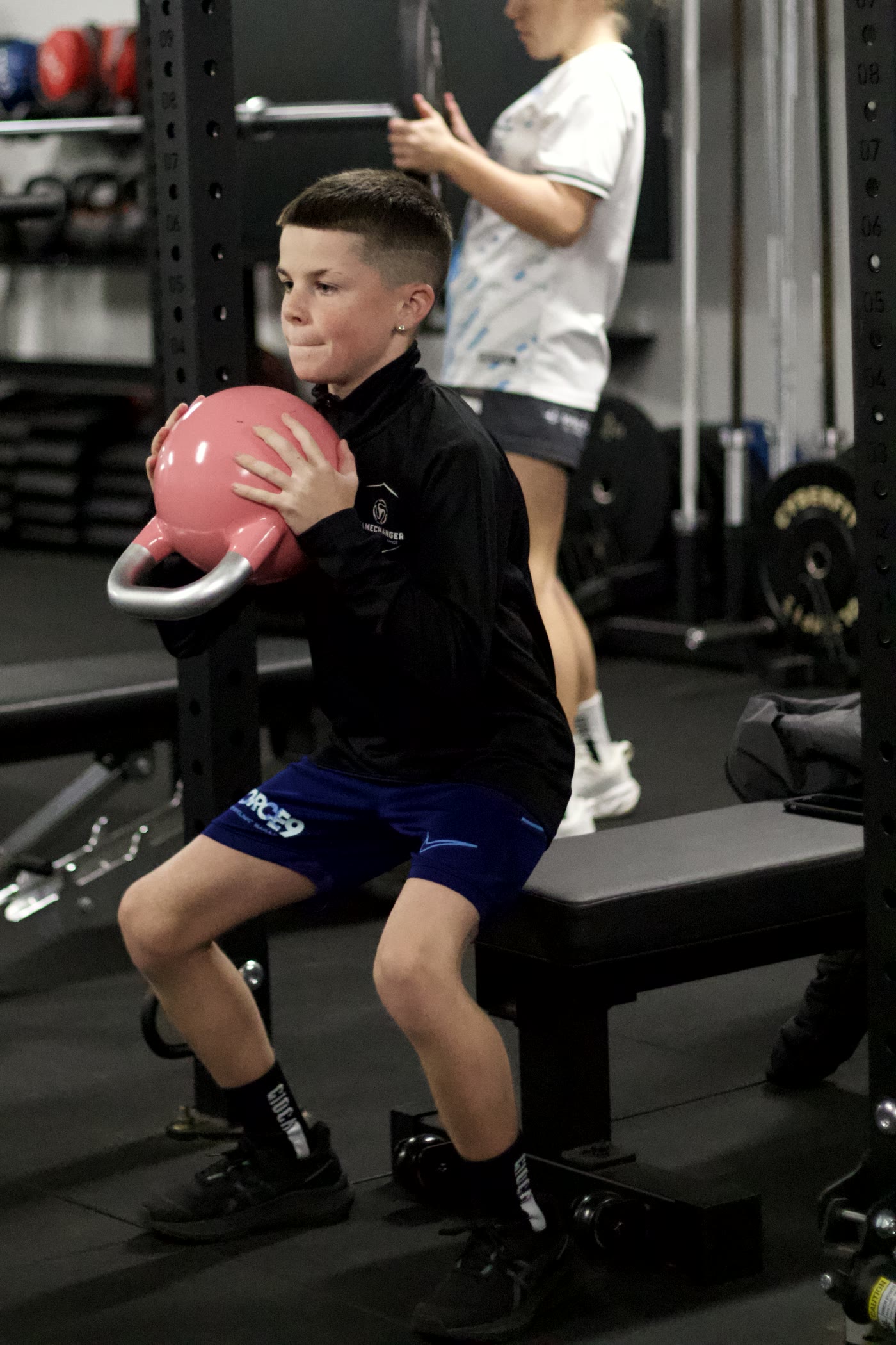 A young athlete coached through a loaded carry in the Gamechanger gym.