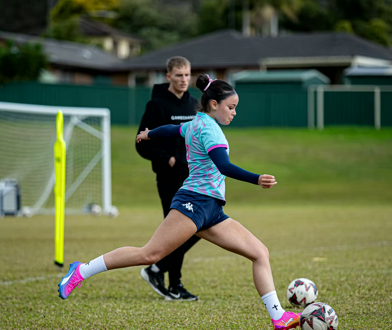A Gamechanger player striking the ball under a coach's eye at training in South West Sydney.