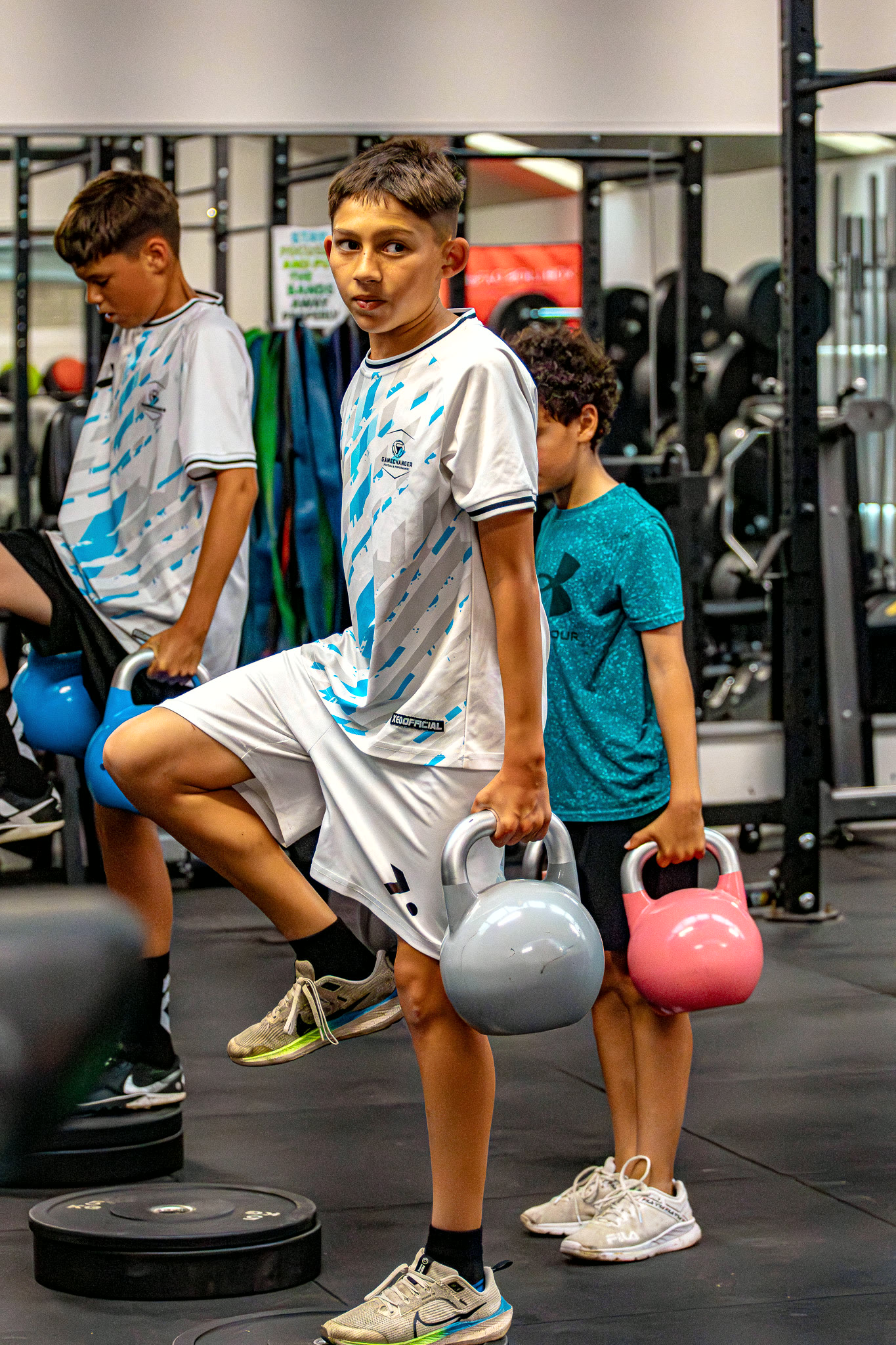 A Gamechanger athlete stepping up with kettlebells during a small-group session in the private gym.